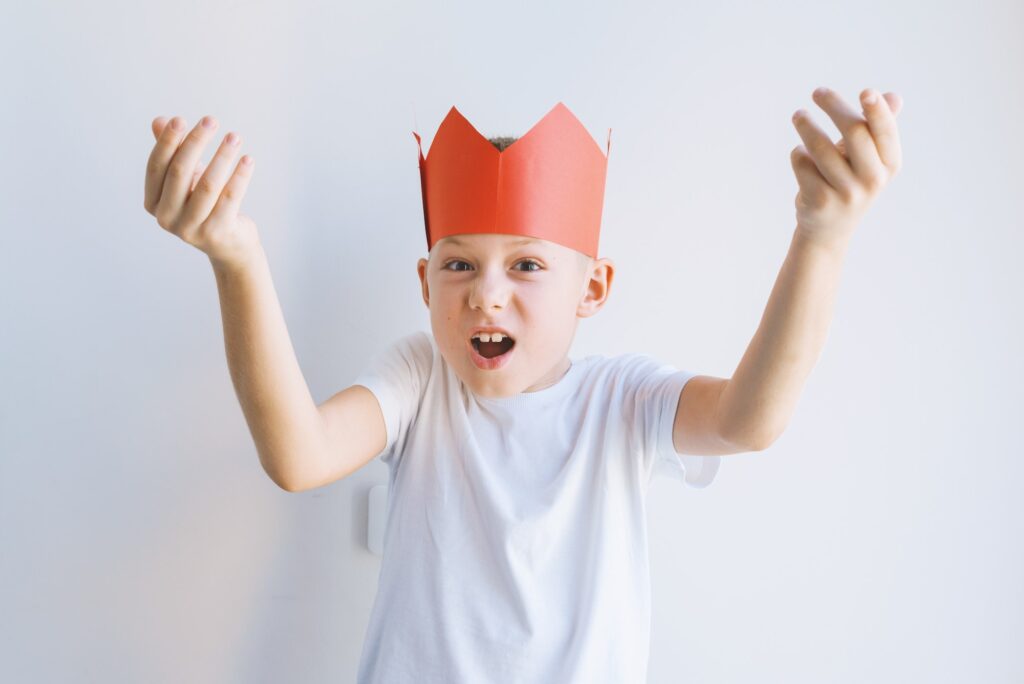 Boy in red paper crown showing weak government concept. Copying behavior model of failure of adult o