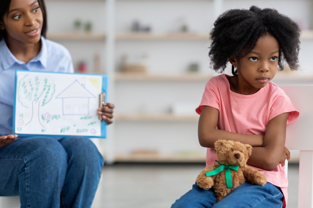 Child psychotherapist showing little girl clipboard with drawing